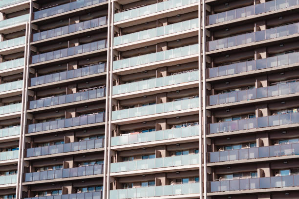 Modern high-rise apartment building featuring multiple balconies on each floor, showcasing architectural symmetry and urban living. Glass railings provide a stylish and contemporary appearance, highlighting the sleek design and functionality of modern residential architecture.
