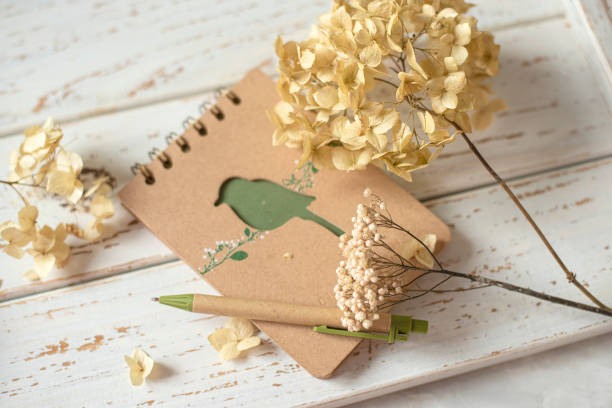 istock Notepad and dried flowers on a white wooden background. View from above. 2158713474