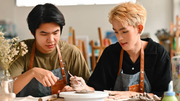 istock A teacher guides an LGBT student in decorating patterns on clay in a bright, creative studio, focusing intently on the pottery piece, showcasing the art of ceramics, Crafts and DIY concept 2158717462