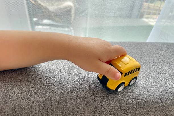 istock A child's hand is playing with a yellow small toy car 2158718030