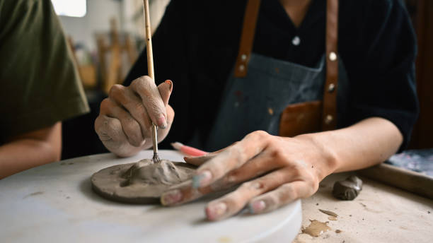 istock A person forming a ceramic piece on a pottery wheel, using both hands and a sculpting tool, concentrating on shaping the clay, Crafts and DIY with people concept 2158718367