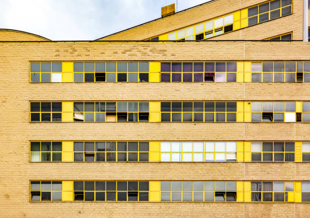 A sleek blue architectural facade frames a bold yellow doorway into a bright, glossy lobby. Blurred pedestrians convey motion and energy, highlighting a dynamic urban corporate atmosphere.