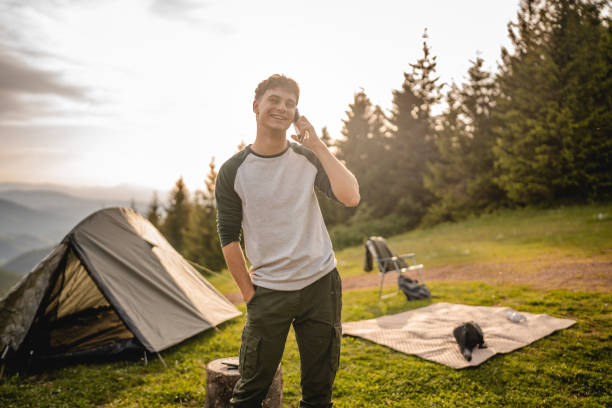 istock Young boy stand in front tent and talk on mobile phone on the mountain 2158720355