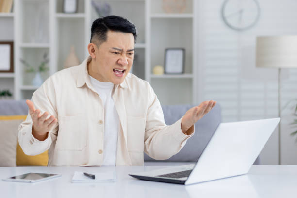 istock Frustrated man expressing anger at computer screen in home office 2158720583