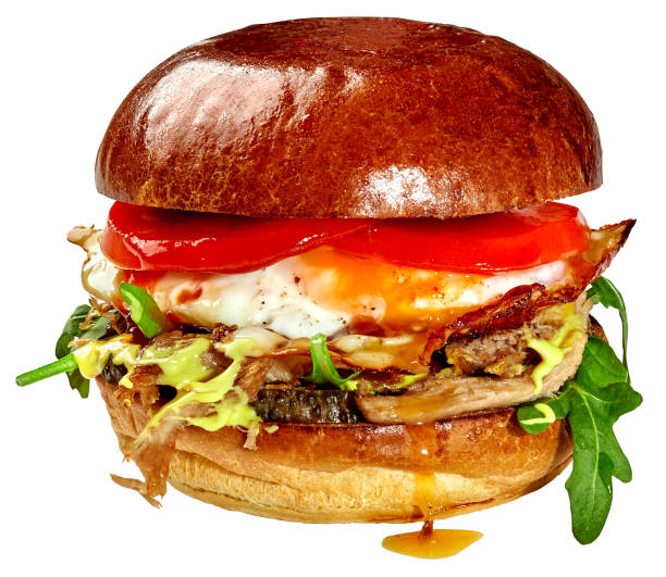 Large hearty burger in fluffy bun with pulled pork, fried egg, pickles, caramelized onions, tomatoes, fresh arugula and cheese sauce isolated in white background