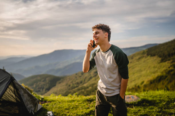 istock Young boy stand in front tent and talk on mobile phone on the mountain 2158722096