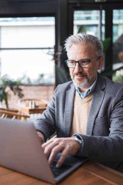 istock Mature businessman working remotely from a modern office space, using a laptop. The image captures focus, productivity, and a professional atmosphere. 2158729030