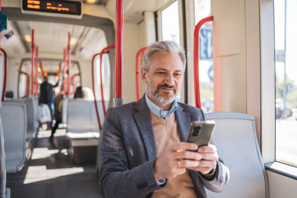 istock Mature businessman riding a train and using a smartphone for remote work. The professional is dressed in a blazer, looking focused and engaged while commuting during daytime. 2158729052