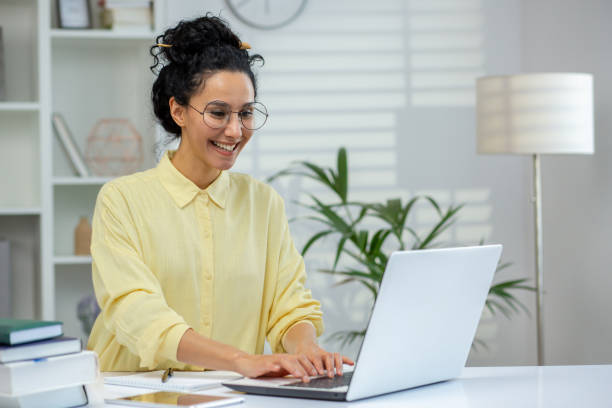 istock Smiling woman working on laptop at home office desk. 2158729446