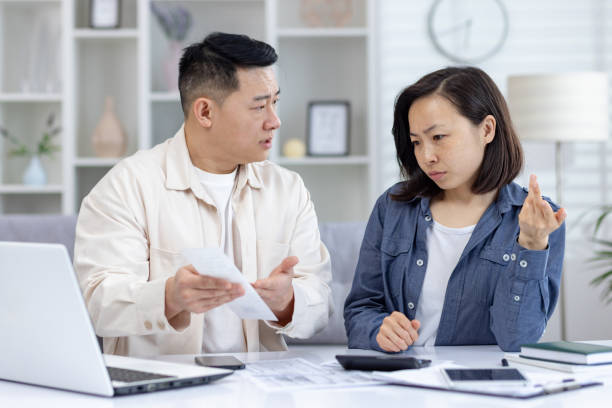 istock Couple discussing financial issues at home with a laptop and bills on the table 2158730461