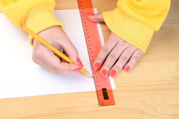 istock Women's hands draw lines on paper using a ruler and pencil. 2158736101
