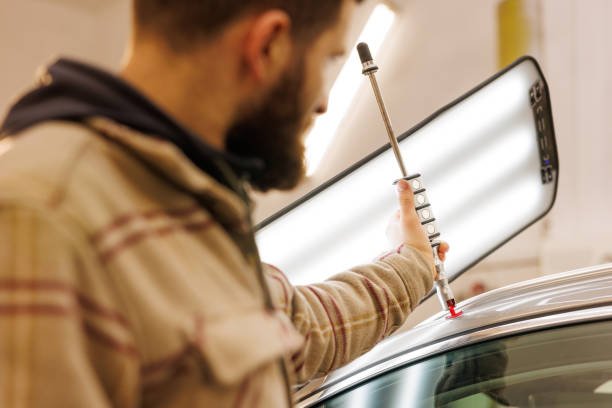 istock Man fixing car with light on, working on vehicles roof 2158745711