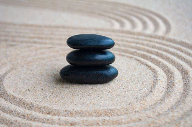 istock Black zen stones inside lines carved on sand with customizable space for text 2158745729
