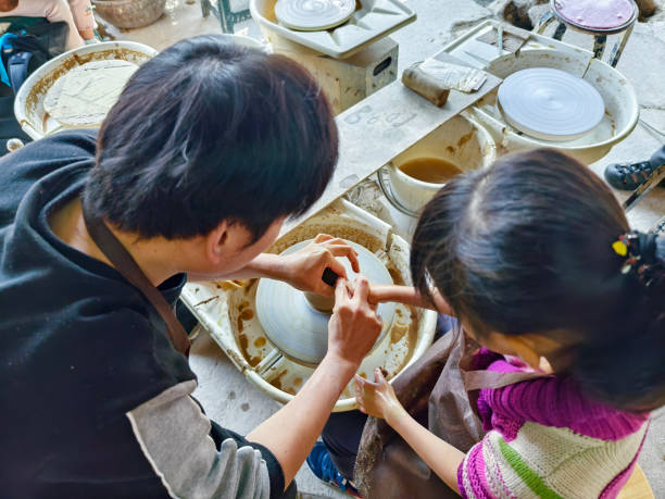 An Asian father accompanies his two daughters to knead clay with their hands. The actual experience is an activity that is highly valued in education nowadays.