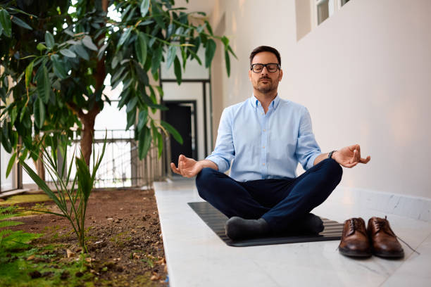 istock Businessman in lotus pose practicing Yoga while working in the office. 2158752348