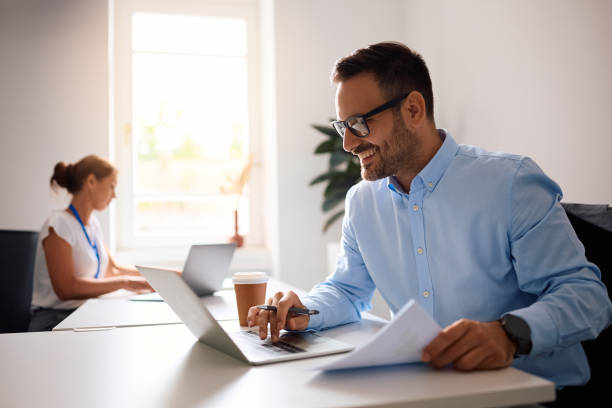 istock Happy entrepreneur using laptop while working on business reports in the office. 2158752400