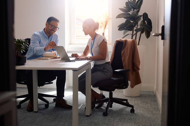 istock Happy colleagues cooperating while working on laptop in the office. 2158752939