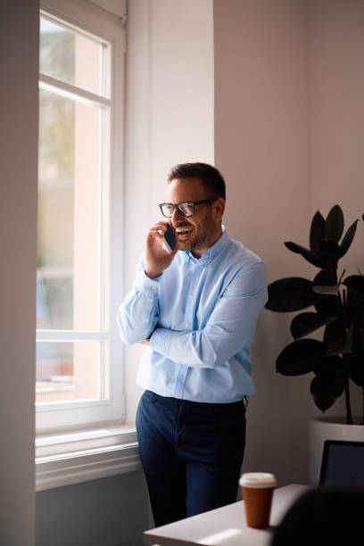 istock Happy entrepreneur talking on mobile phone by the window in the office. 2158752959
