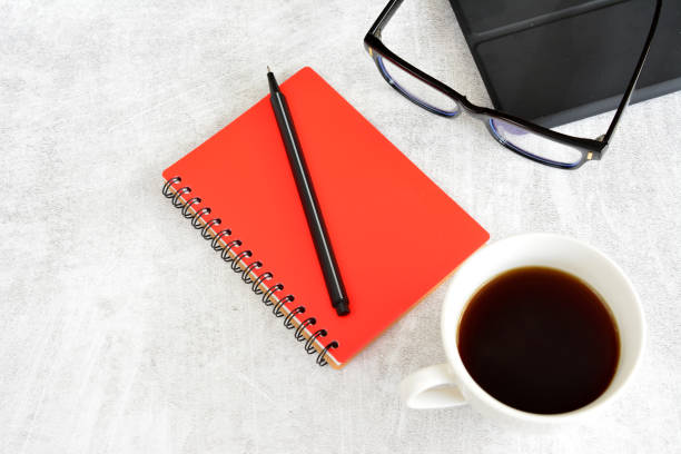 istock a red notebook with a black pen on it and a pair of glasses on a table 2158754571