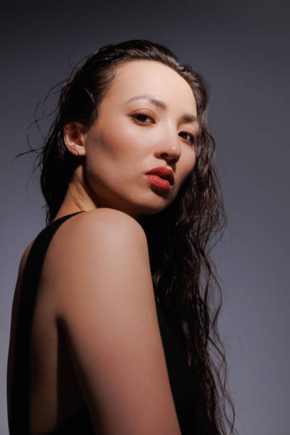 istock Stylish asian woman with red lips looking at camera on grey background 2158763102