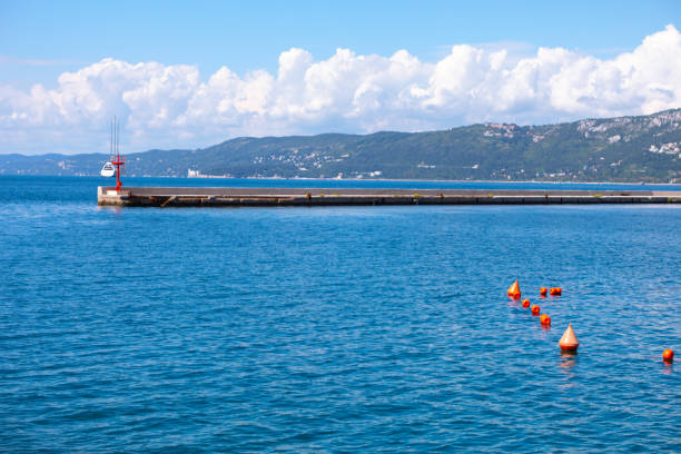 Landscape with of Adriatic Sea in Trieste Italy. Calm blue sea with a red lighthouse in the distance