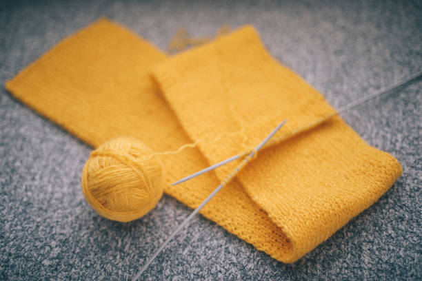 Knitting a scarf for a winter, ball of yellow wool and knitting needle.