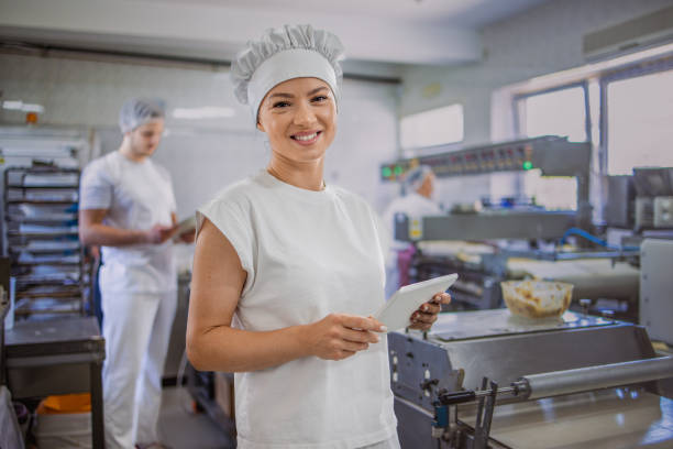 istock Female chef holding tablet in bakery, man working behind 2158772932