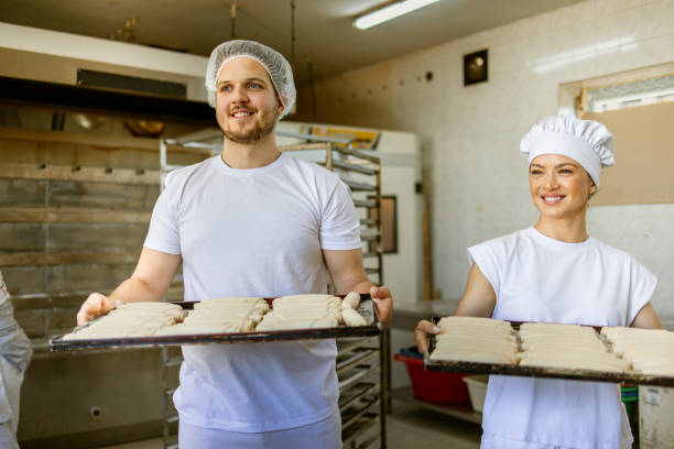 istock Chefs holding trays of pastries in industrial bakery kitchen 2158772951