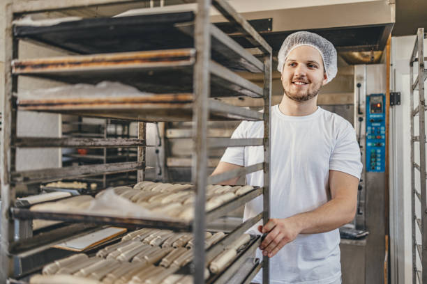 istock Baker moving freshly baked bread from oven racks in a bakery kitchen 2158773132