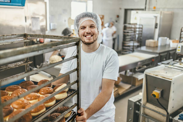 istock Bakery worker smiles while transporting freshly baked pastries in a commercial kitchen 2158773242