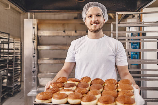 istock Baker holding freshly baked pastries in a commercial bakery 2158773791