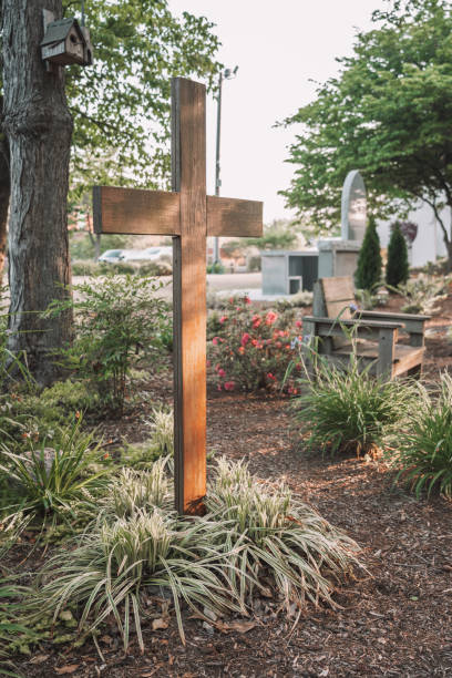 Sunrays illuminate the hills valleys behind an old wooden cross.