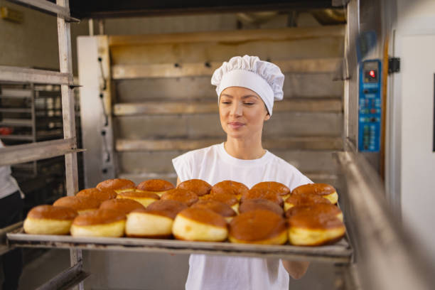 istock Baker carrying freshly baked doughnuts in a bakery 2158773965