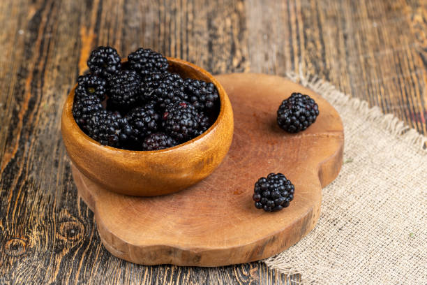 istock black ripe blackberries on the table in a wooden bowl 2158778546
