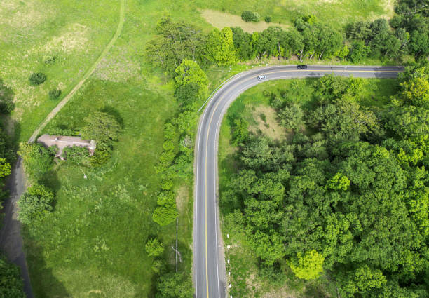 looking down at empty road from above (drone shot of highway) green trees landscape countryside driving scenic country usa north america