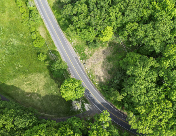 istock looking down at empty road from above (drone shot of highway) green trees landscape countryside driving scenic country usa north america 2158779653
