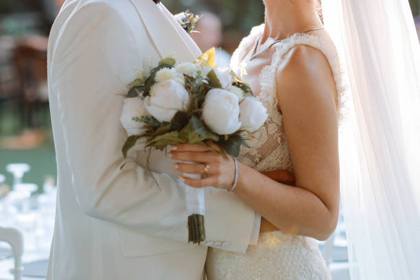 Bride and groom outdoors on a wedding day Happy bride and groom on their wedding hugging. Closeup Bride holding a bouquet hands of bride and bridegroom in wedding marriage ceremony stock pictures, royalty-free photos & images