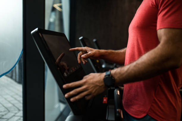 istock Athletic man running on treadmill and adjusting settings on touch screen in a gym. 2158784579