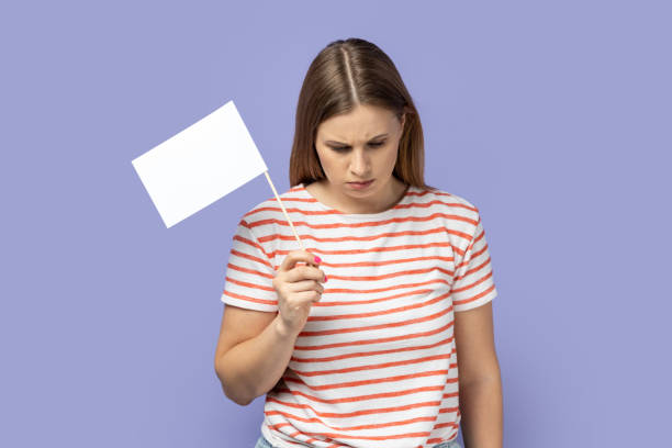 Woman standing with head down, holding white flag, giving up, expressing sorrow.