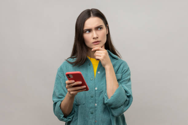 istock Pensive thoughtful woman thinks about answering message on smartphone and looking away. 2158792887