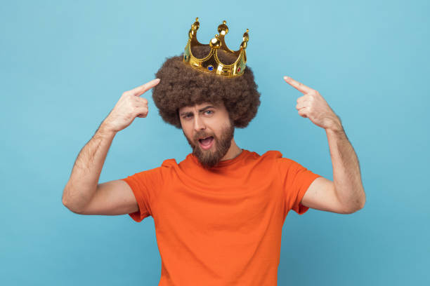 istock Man standing and pointing at golden crown, looking at camera with proud expression. 2158792915