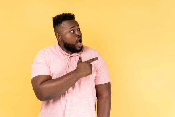 istock Man looking away with surprised amazed expression, pointing aside at copy space. 2158792923