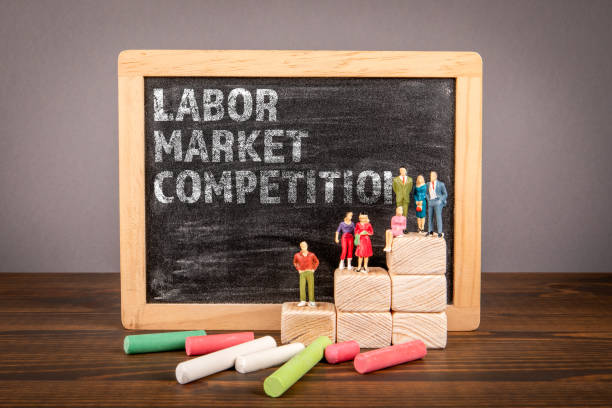 istock Labor Market Competition. Chalk board with text and miniature human figures on a wooden table 2158794131