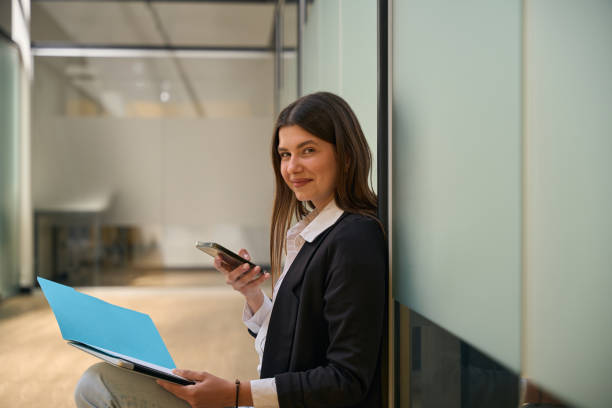 istock Smiling woman holding phone and looking at camera 2158798750