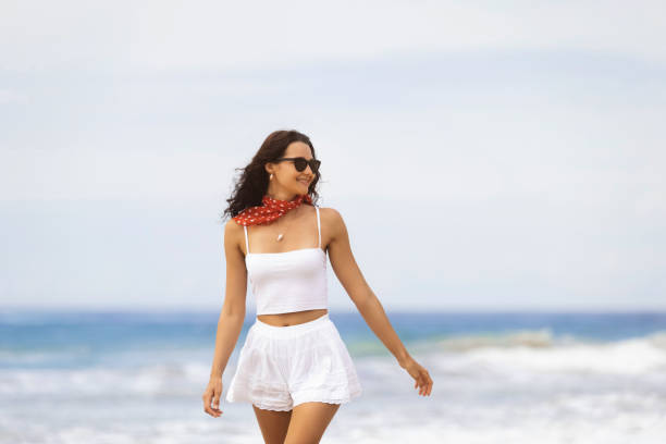 Woman in White Outfit Strolling on Beach