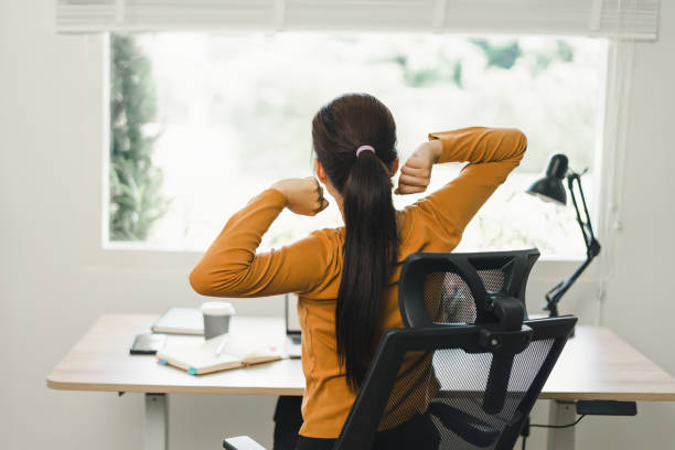 istock Woman taking a break and stretching at desk in home office. 2158802506