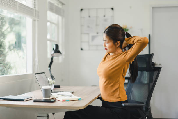 Woman taking a break and stretching at desk in home office.