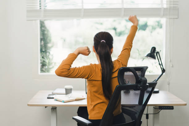 istock Woman taking a break and stretching at desk in home office. 2158802511