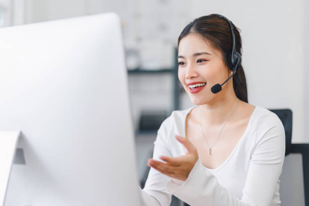 istock Smiling woman wearing headset, participating in video conference call from home office, using computer for virtual communication. 2158802537