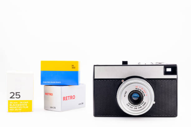 film camera and 35mm film roll and film box, close-up side view, on white background